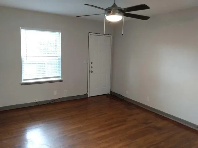 an empty room with wooden floor closet and windows