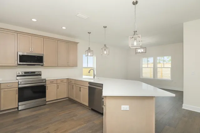 a kitchen with stainless steel appliances granite countertop a sink a stove a microwave oven a refrigerator with white cabinets and wooden floor