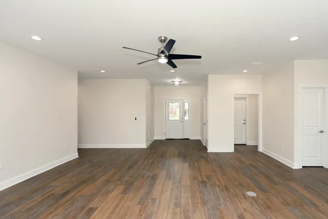 an empty room with wooden floor and a ceiling fan
