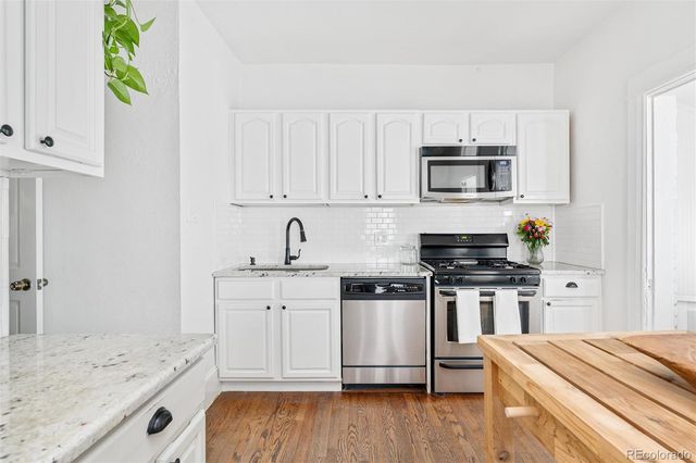 a kitchen with stainless steel appliances granite countertop a stove a sink and a microwave