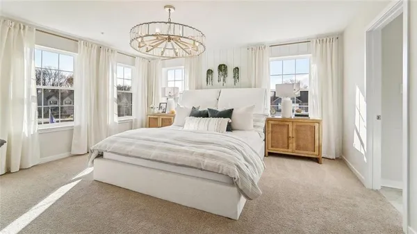 a spacious bedroom with a bed a dresser and windows