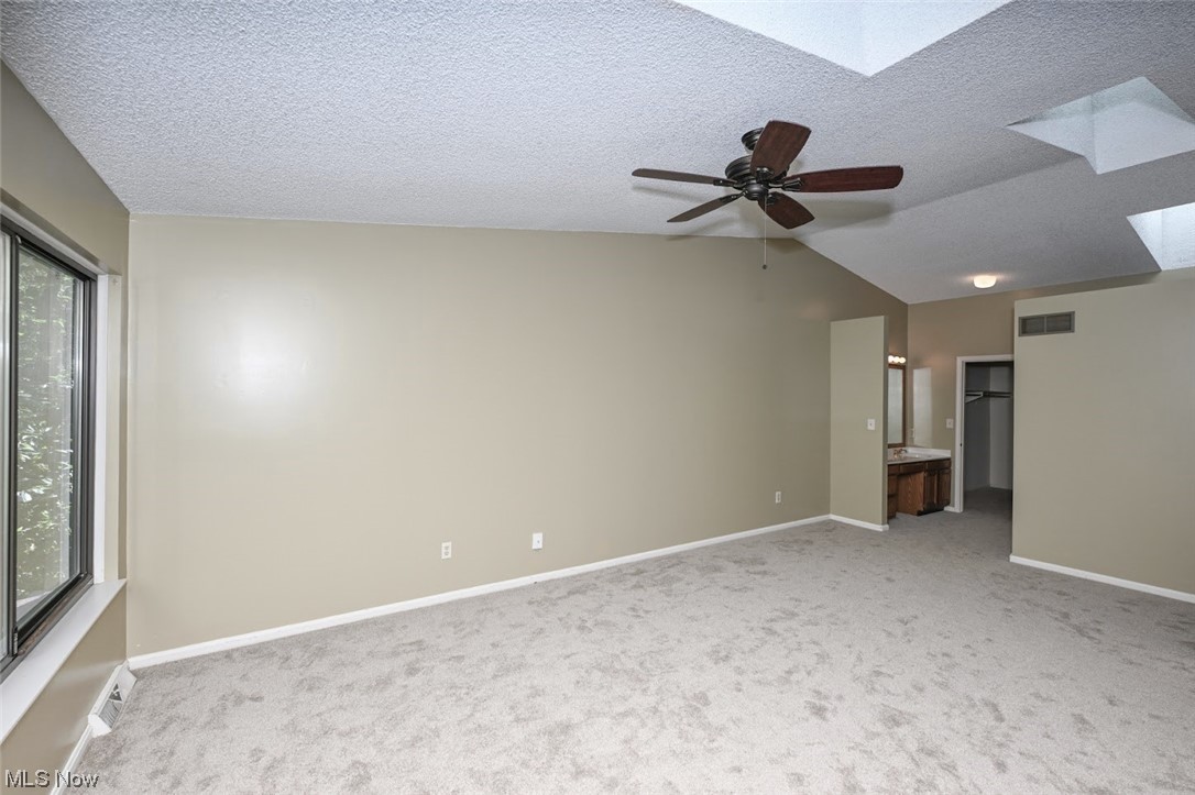 646 Hampton Ridge Drive Akron, OH 44313 - Photo 21 of 33 Carpeted empty room featuring a textured ceiling, lofted ceiling, and ceiling fan