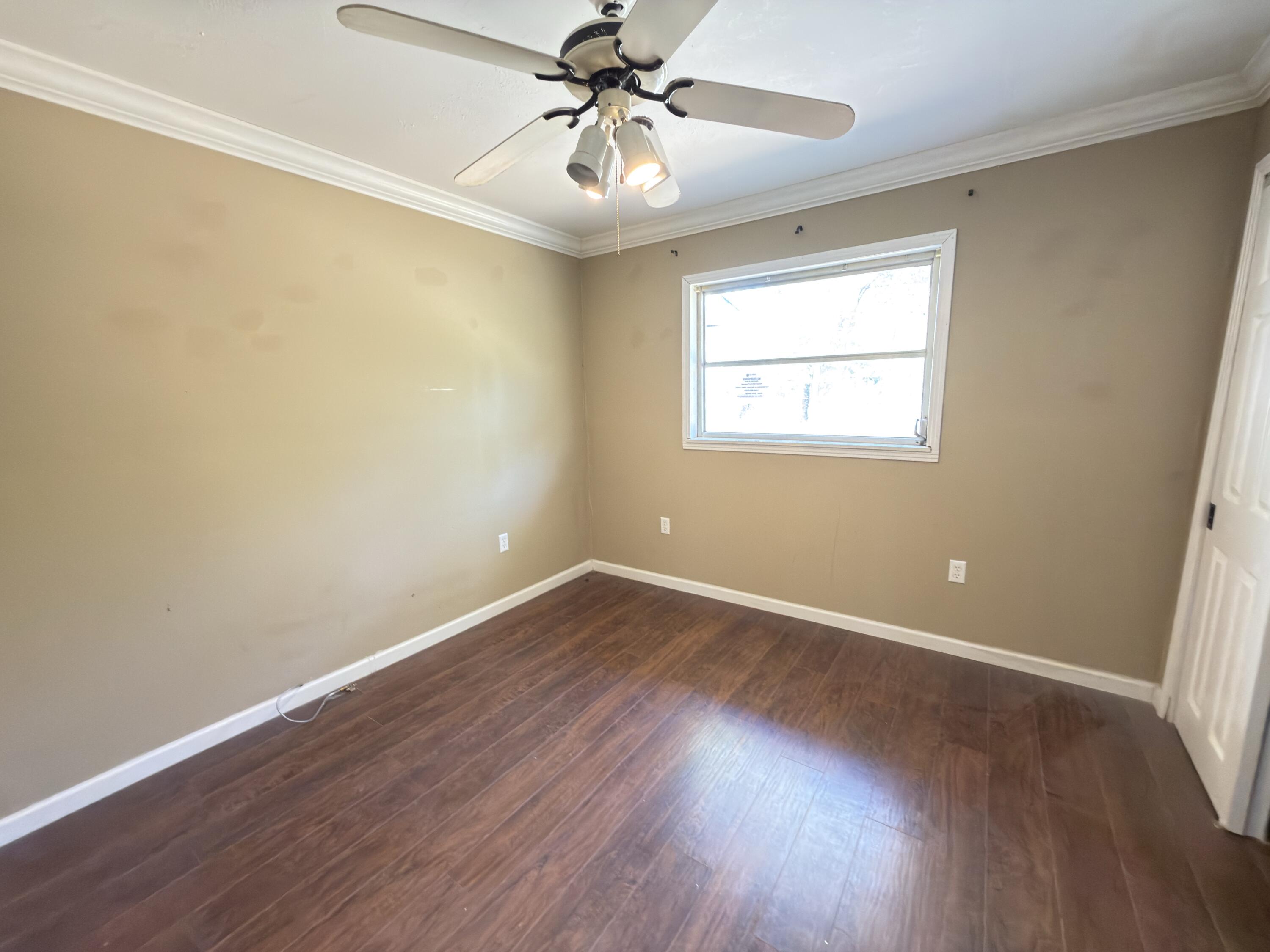 515 Robinson Avenue East Crestview, FL 32539 - Photo 17 of 22 an empty room with wooden floor chandelier fan and windows