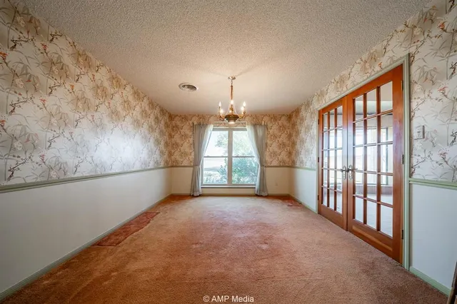 an empty room with chandelier fan and windows