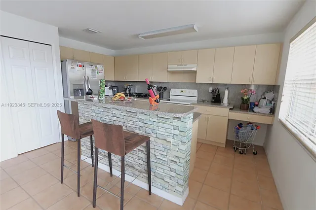 a kitchen with a dining table chairs sink and white appliances