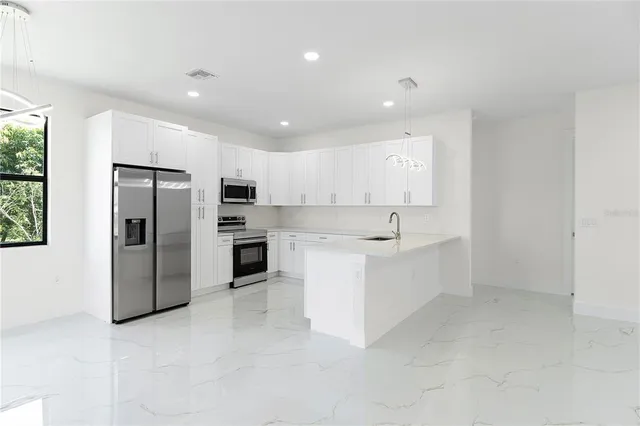 a large white kitchen with a refrigerator a sink dishwasher a oven with white cabinets and a refrigerator