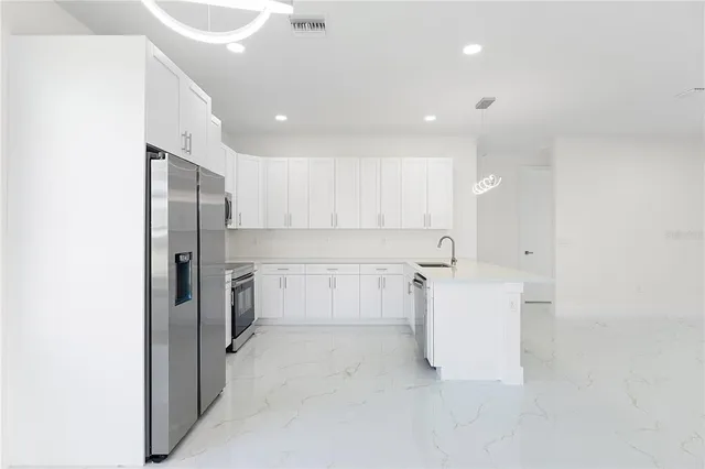 a large white kitchen with a sink and dishwasher a refrigerator with white cabinets