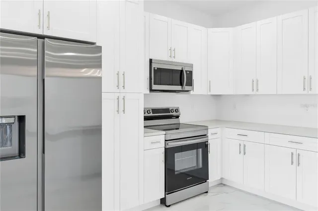 a kitchen with white cabinets and stainless steel appliances