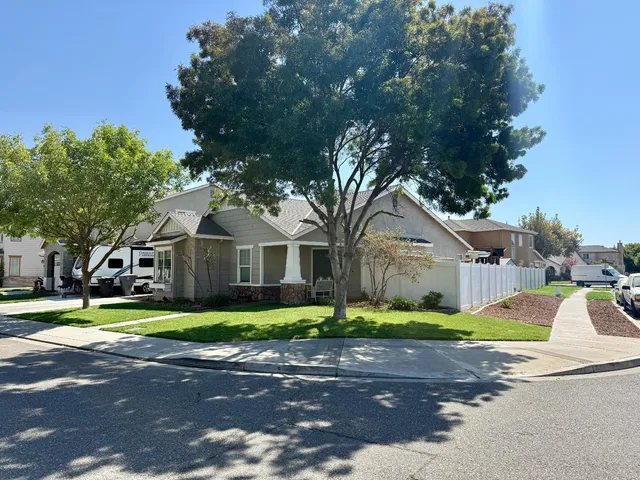 a front view of a house with a garden and trees