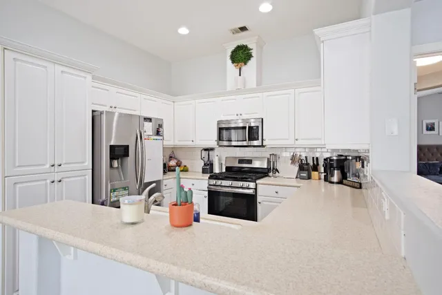 a kitchen with stainless steel appliances granite countertop a sink and white cabinets