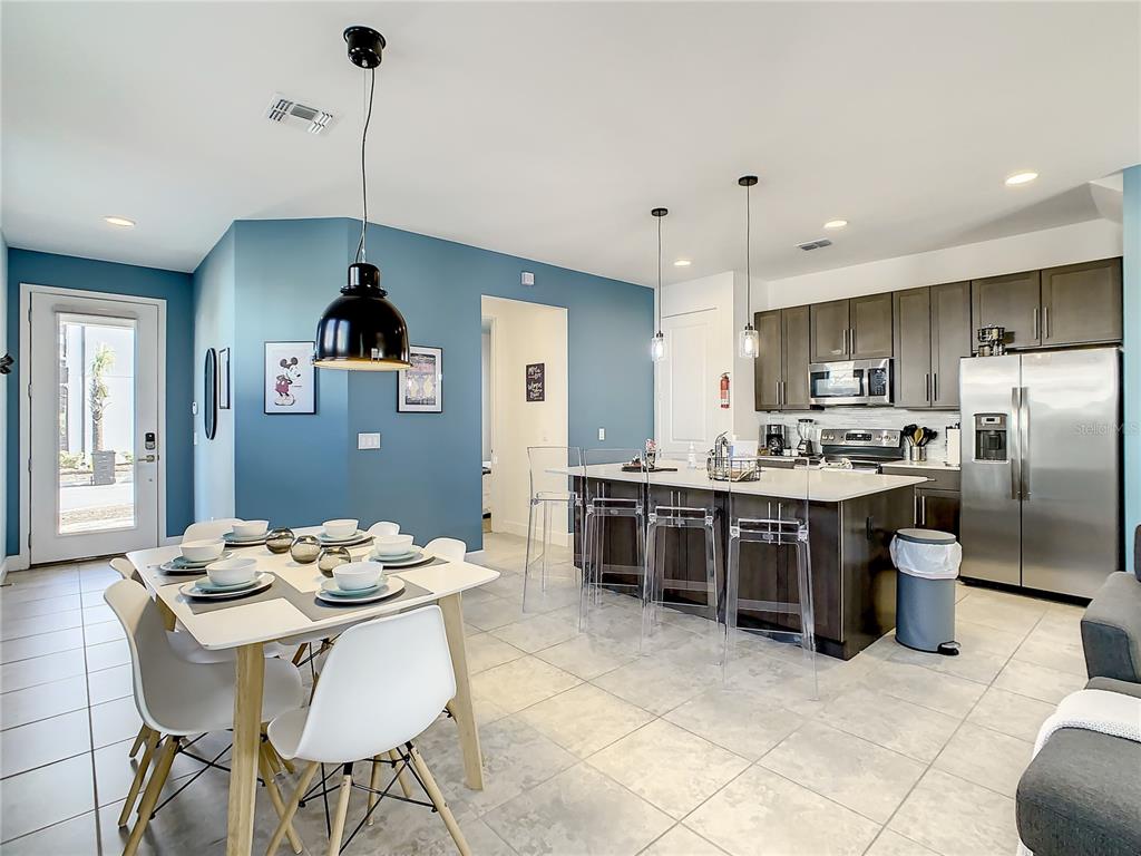 181 Villa Domani Circle Davenport, FL 33896 - Photo 14 of 37 a kitchen with stainless steel appliances kitchen island granite countertop a sink a stove a refrigerator and a dining table