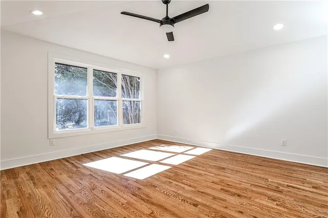 an empty room with wooden floor cabinet and windows