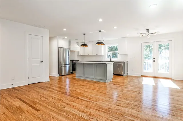 a large white kitchen with wooden floors and stainless steel appliances