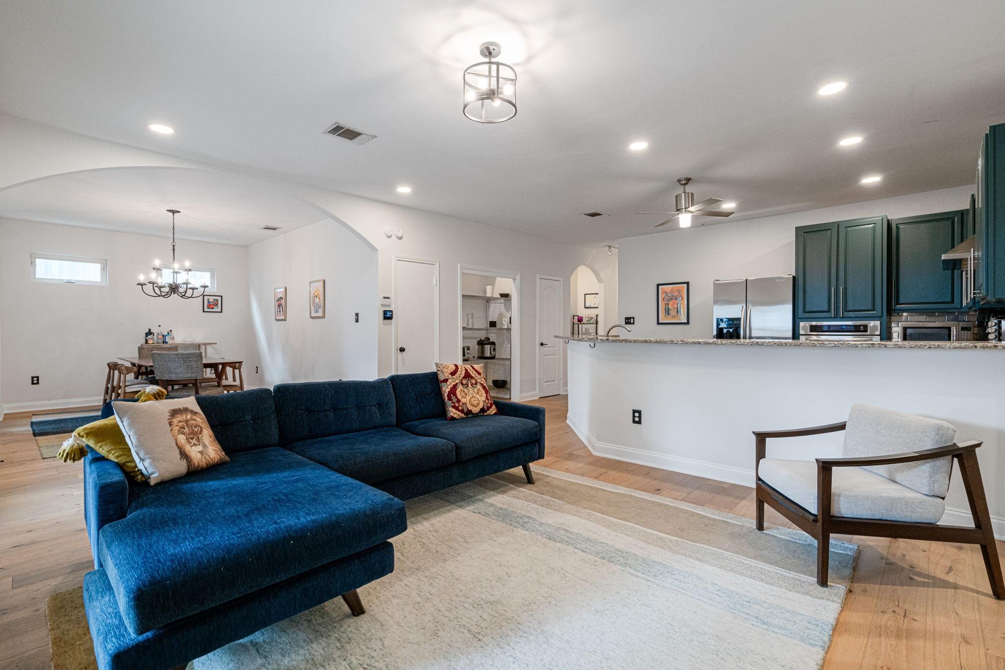 72 San Saba Street Austin, TX 78702 - Photo 5 of 23 Living room with arched walkways, light wood finished floors, and suspended lighting