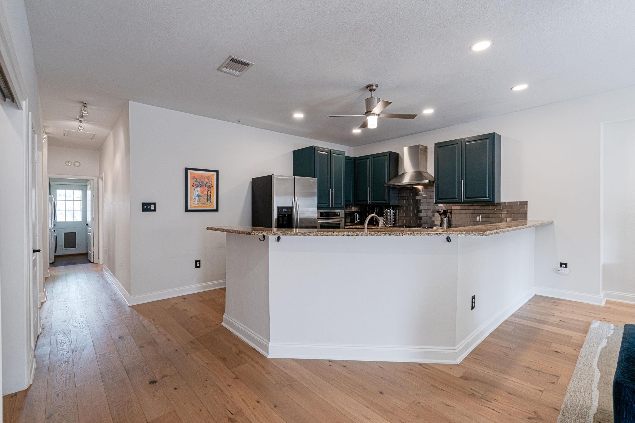72 San Saba Street Austin, TX 78702 - Photo 7 of 23 Kitchen featuring stainless steel appliances, light wood-type flooring, a peninsula, and tasteful backsplash
