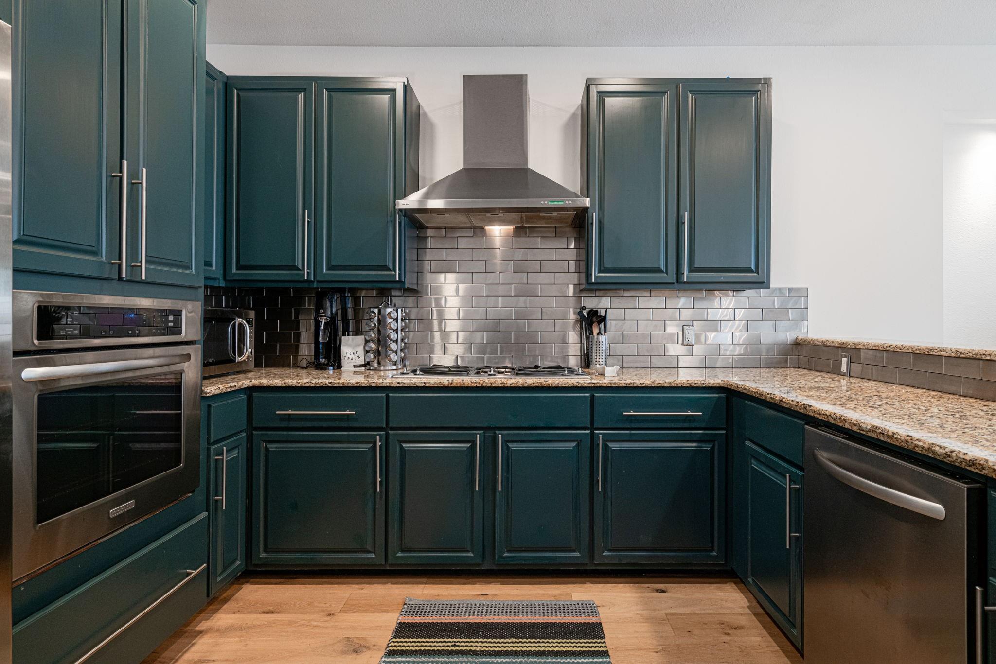 72 San Saba Street Austin, TX 78702 - Photo 8 of 23 Kitchen with stainless steel appliances, light stone countertops, light wood finished floors, and backsplash