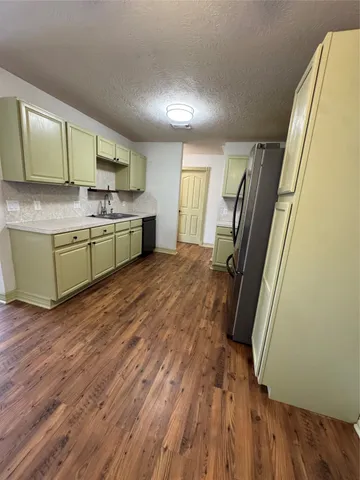 a kitchen with stainless steel appliances granite countertop a refrigerator a sink dishwasher a stove and white countertops with wooden floor