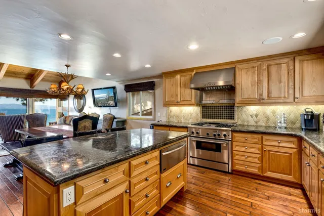 a kitchen with granite countertop stainless steel appliances a stove a sink a counter top space and cabinets