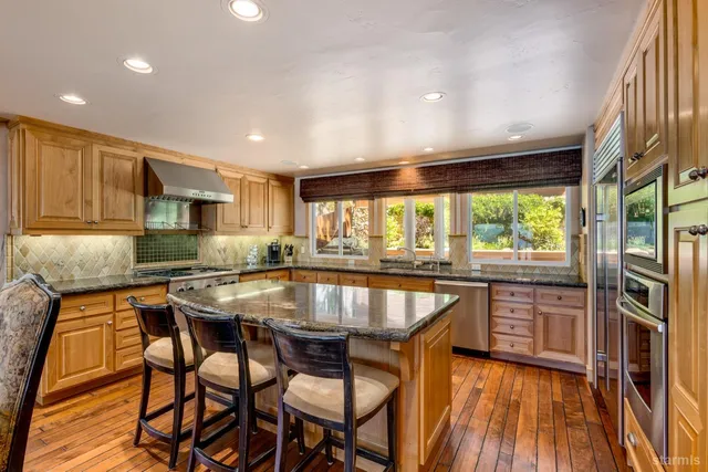 a kitchen with stainless steel appliances granite countertop dining table chairs sink and wooden floor