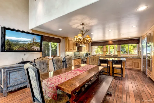 a living room with furniture a chandelier and a dining table with wooden floor