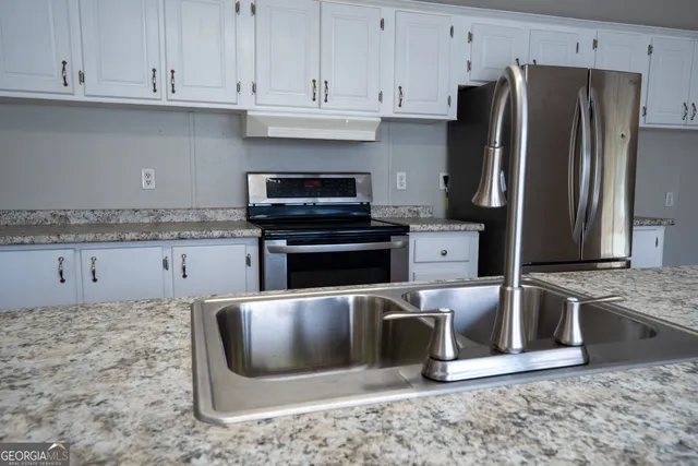 a kitchen with stainless steel appliances granite countertop a stove a refrigerator and a sink