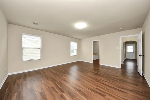 an empty room with wooden floor and windows