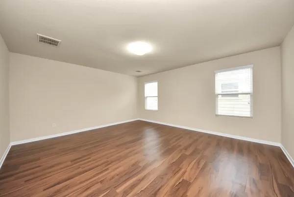 an empty room with wooden floor and windows