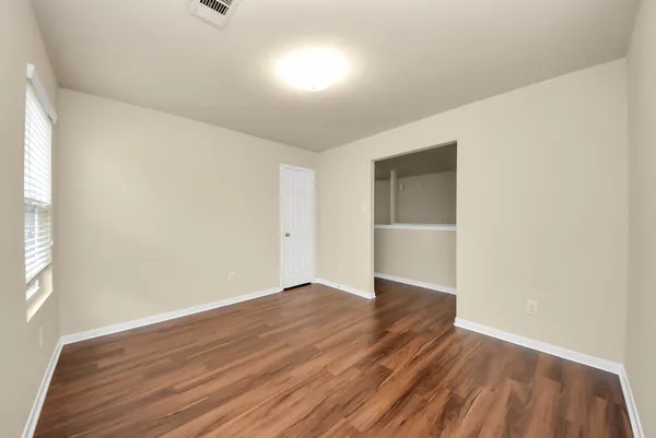 an empty room with wooden floor and windows