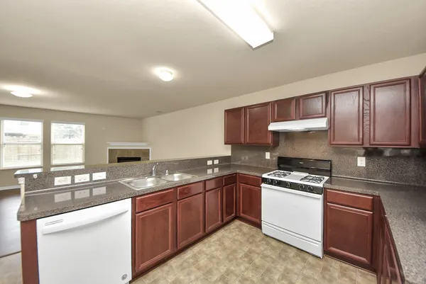 a kitchen with granite countertop stainless steel appliances a sink a stove a counter space and cabinets