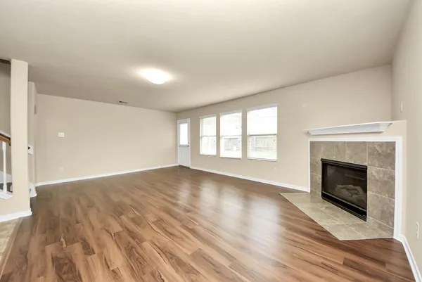 an empty room with wooden floor fireplace and windows