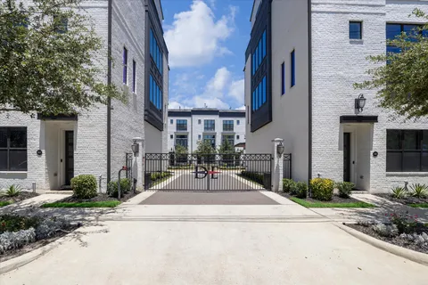 a view of a building with brick walls plants and large tree