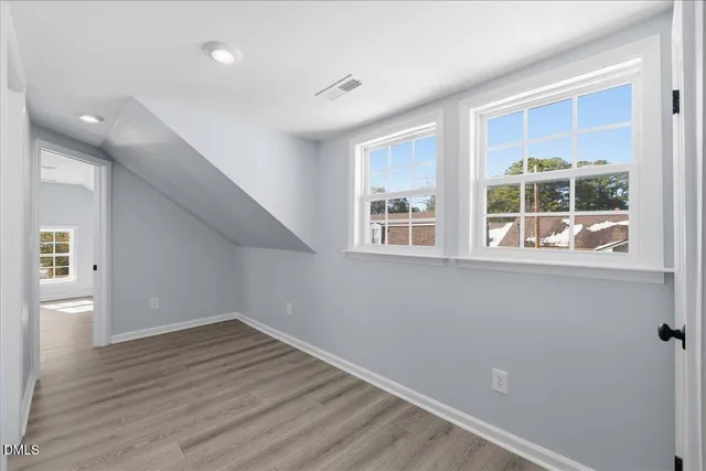 a view of empty room with wooden floor and windows