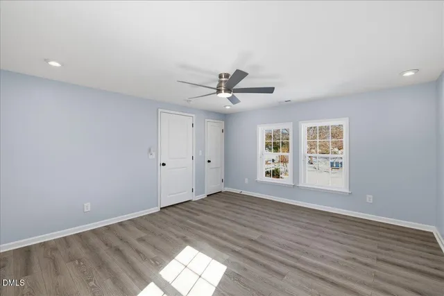 an empty room with wooden floor and windows