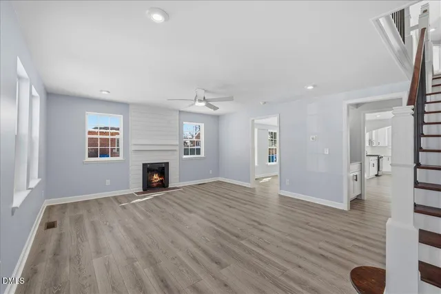 an empty room with wooden floor fireplace and windows