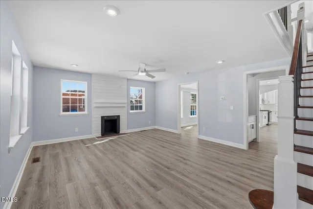 an empty room with wooden floor fireplace and windows