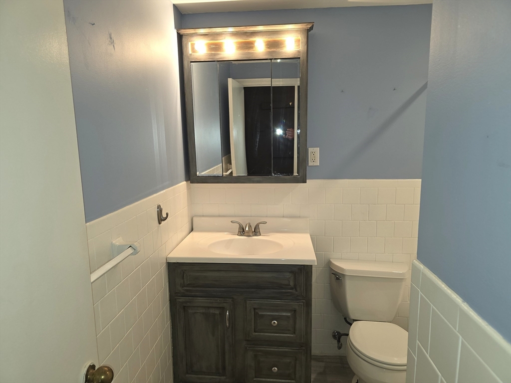 70 Mudge Street, Unit 12 Lynn, MA 01902 - Photo 20 of 22 a bathroom with a toilet sink vanity and mirror
