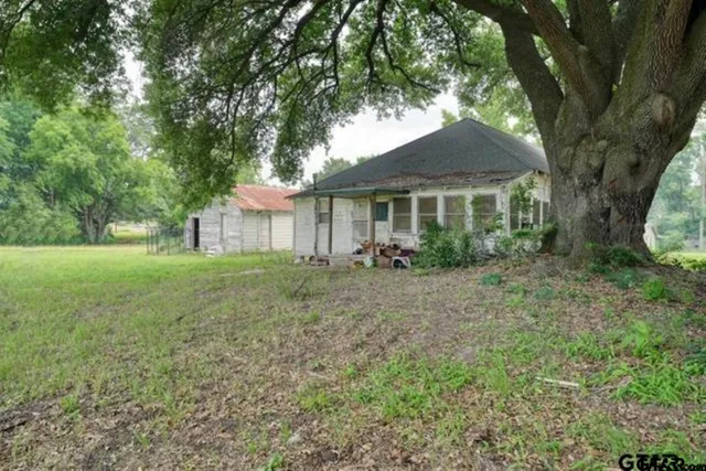 a view of a big house with a big yard and large trees