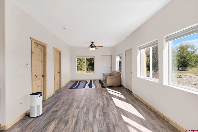 a view of an empty room with a window and wooden floor