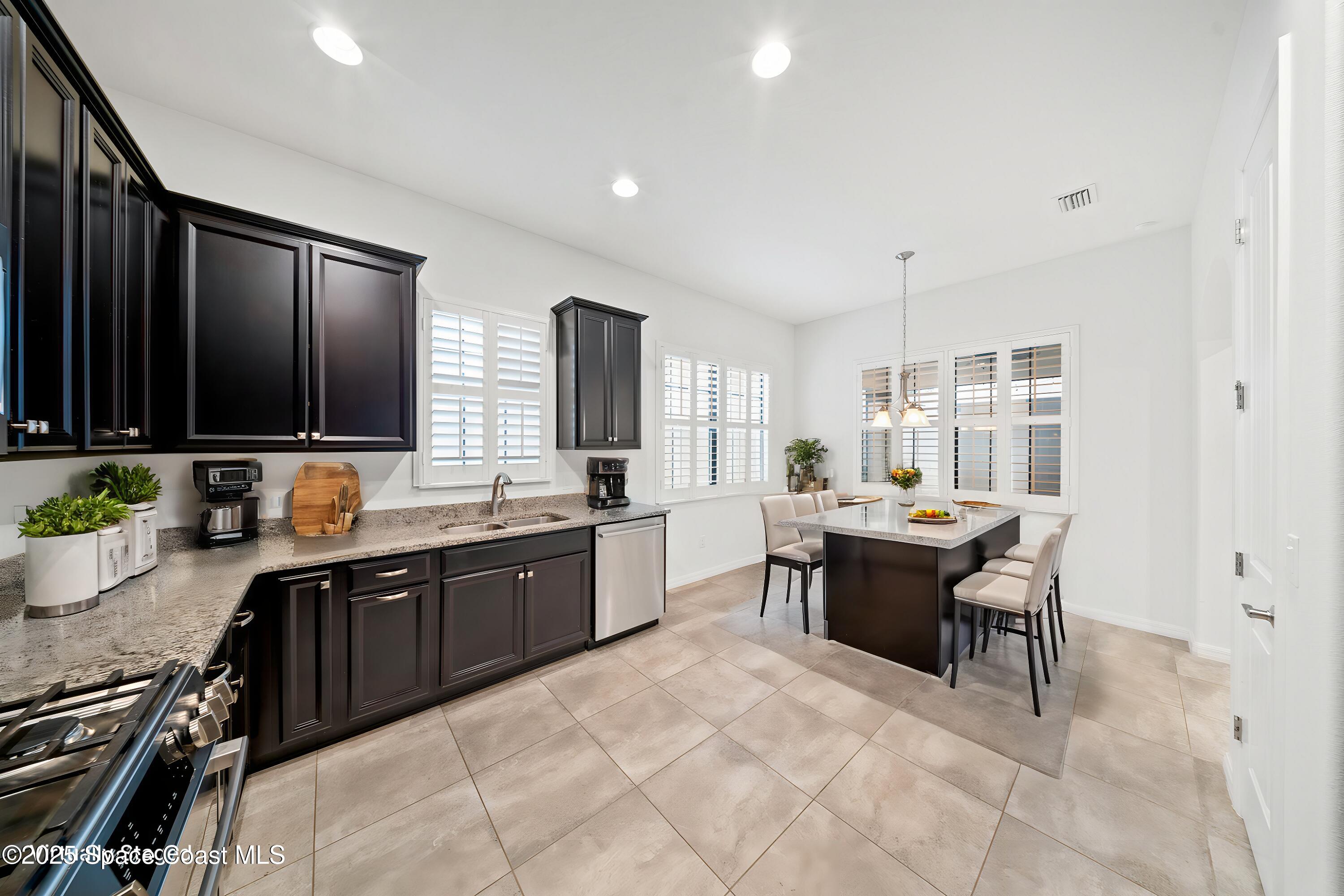 8830 Napolo Drive Melbourne, FL 32940 - Photo 5 of 36 a large kitchen with kitchen island stainless steel appliances a sink table and chairs in it