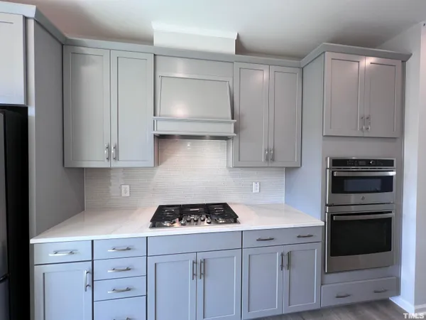 a kitchen with granite countertop white cabinets and stainless steel appliances