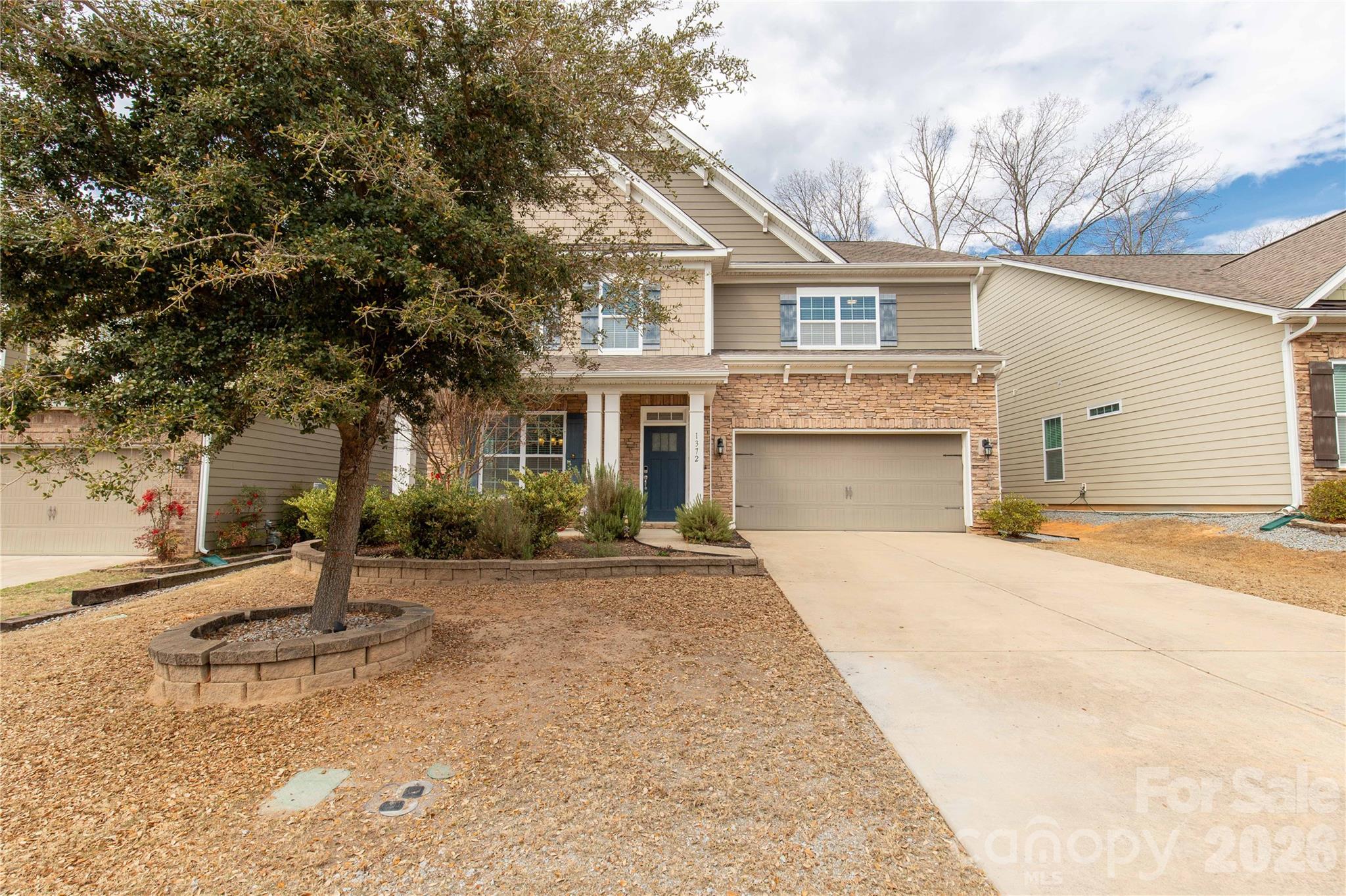 a front view of a house with a garden and trees