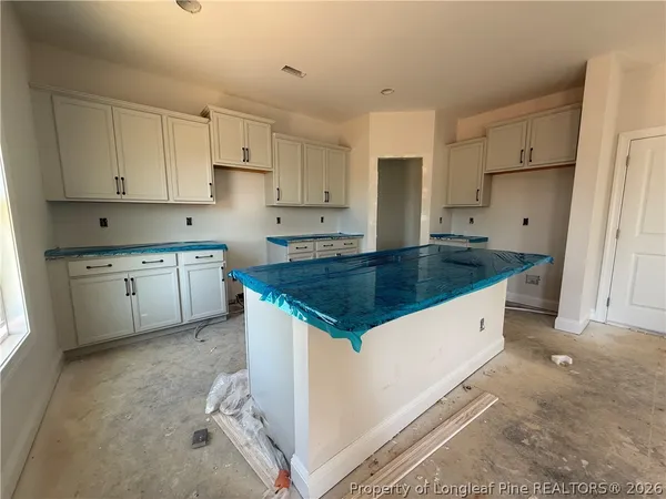 a kitchen with granite countertop a sink a stove a refrigerator and white cabinets