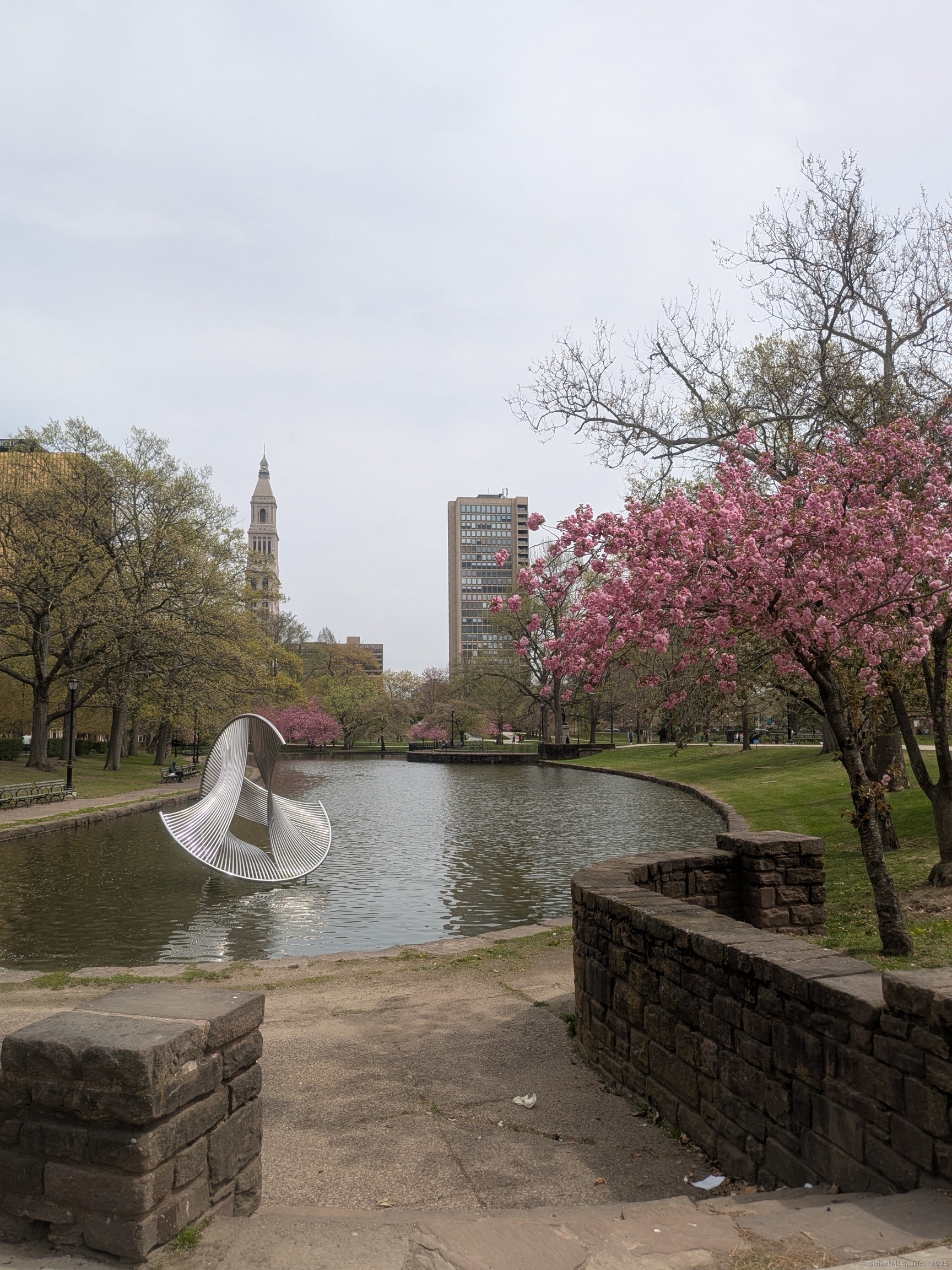 a view of a lake with a bench and trees in the background