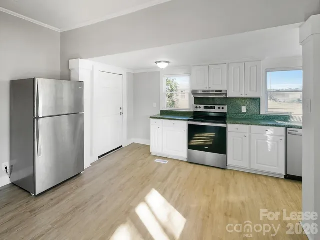 a kitchen with stainless steel appliances white cabinets and wooden floor