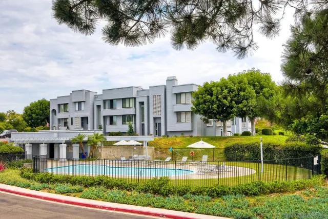 a view of pool with lawn chairs and large trees
