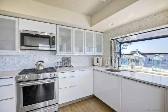 a kitchen with stainless steel appliances granite countertop white cabinets a microwave oven and a sink