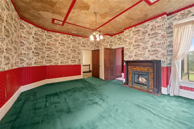 an empty room with wooden floor chandelier fan and windows