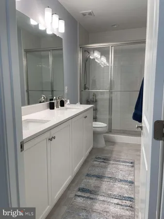 a bathroom with a sink a toilet a mirror and shower