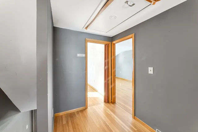 a view of a hallway with wooden floor and a bathroom
