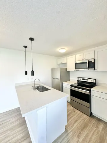 a kitchen with stainless steel appliances kitchen island wooden cabinets stove and sink